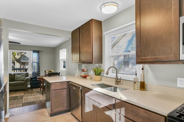 kitchen featuring dishwasher, kitchen peninsula, sink, and light hardwood / wood-style flooring