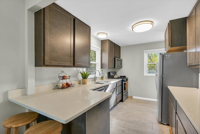 kitchen featuring a wealth of natural light, a breakfast bar, stainless steel appliances, and light wood-type flooring