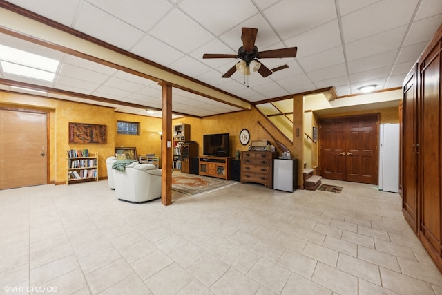 tiled living room with a drop ceiling, ceiling fan, and crown molding