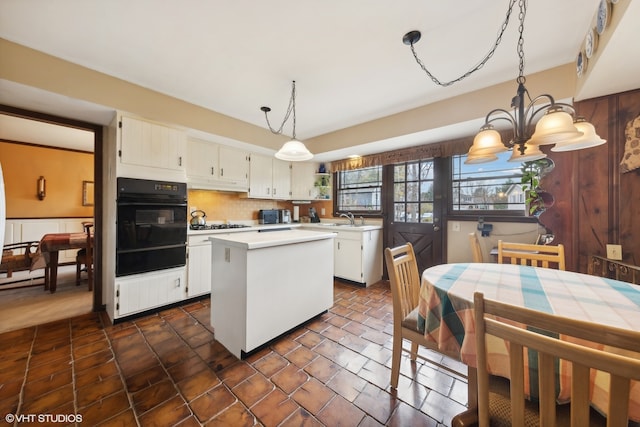 kitchen with a center island, an inviting chandelier, white cabinets, sink, and decorative light fixtures