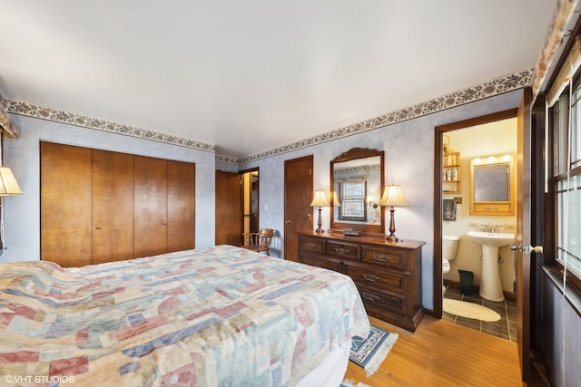 bedroom with connected bathroom, a closet, and light hardwood / wood-style flooring