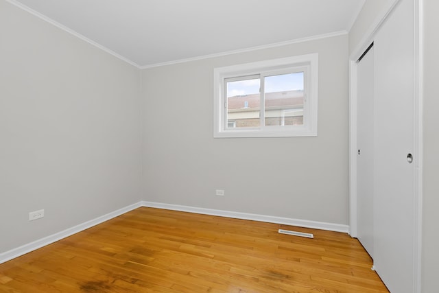 unfurnished bedroom featuring a closet, crown molding, and light hardwood / wood-style floors