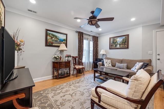 living room with crown molding, ceiling fan, and light hardwood / wood-style flooring