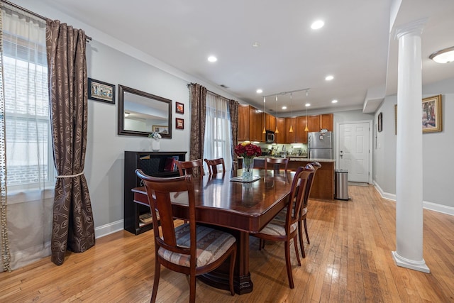 dining area featuring light wood-type flooring, ornate columns, and rail lighting