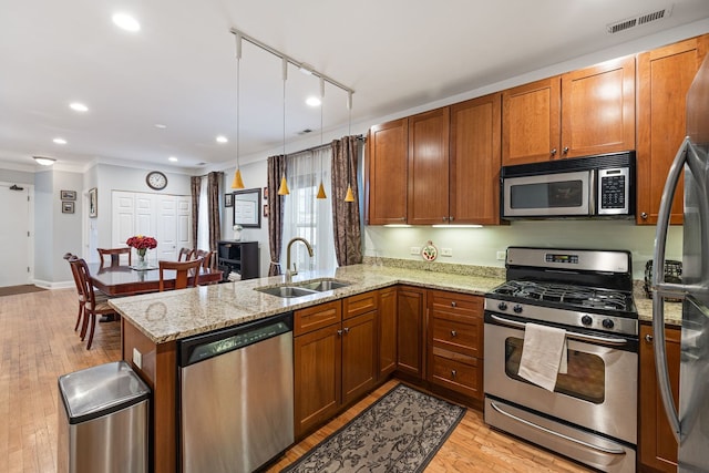 kitchen featuring kitchen peninsula, appliances with stainless steel finishes, sink, and light wood-type flooring