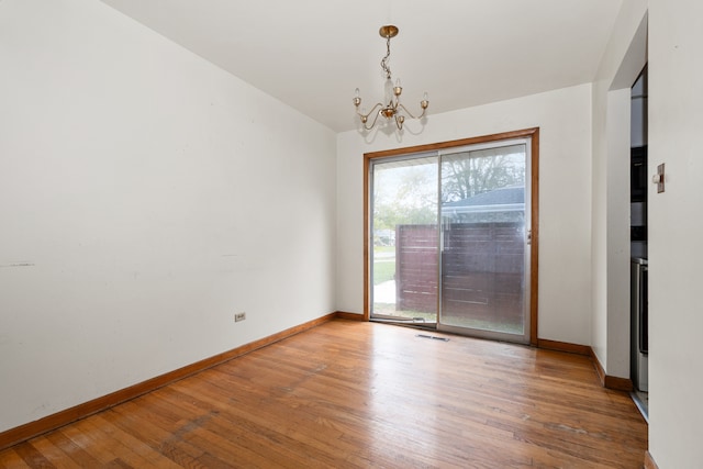 unfurnished room with hardwood / wood-style floors and an inviting chandelier