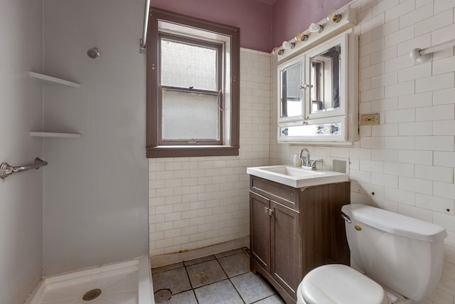 bathroom featuring toilet, tile patterned flooring, vanity, a shower, and tile walls