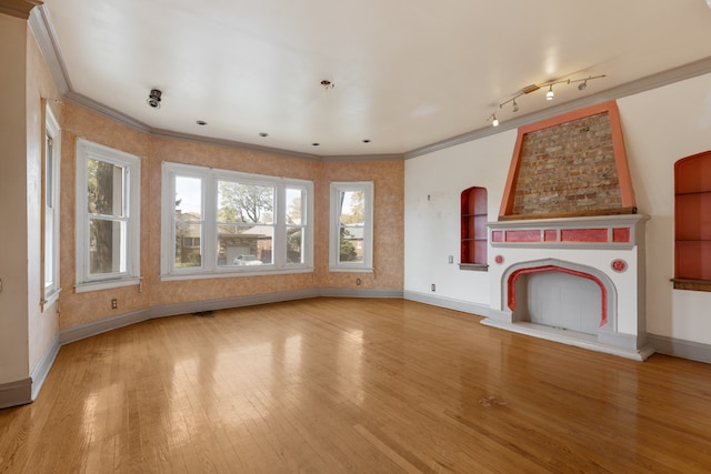 unfurnished living room with crown molding, hardwood / wood-style floors, and rail lighting