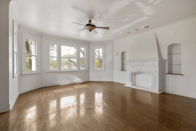 unfurnished living room with dark wood-type flooring, ceiling fan, crown molding, and built in shelves