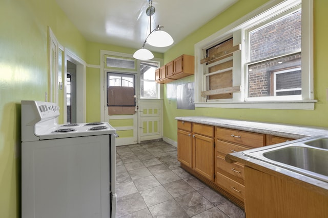 kitchen featuring stove, hanging light fixtures, and sink