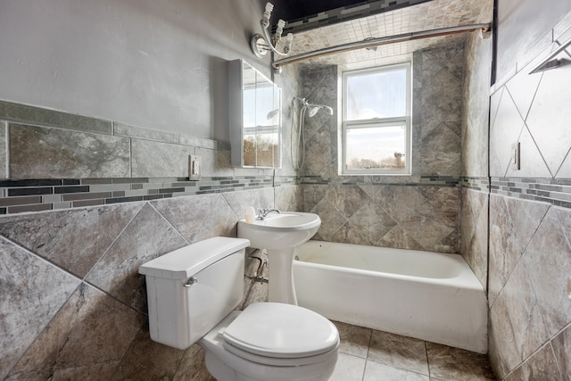 bathroom with toilet, tile walls, and tiled shower / bath