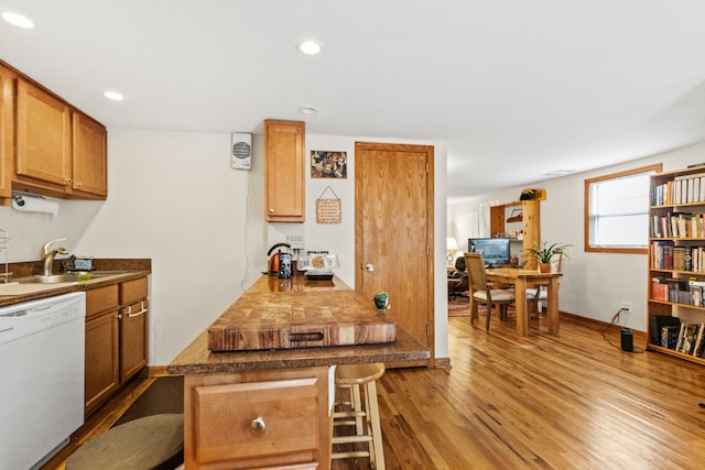 kitchen featuring a breakfast bar area, sink, white dishwasher, and wood-type flooring