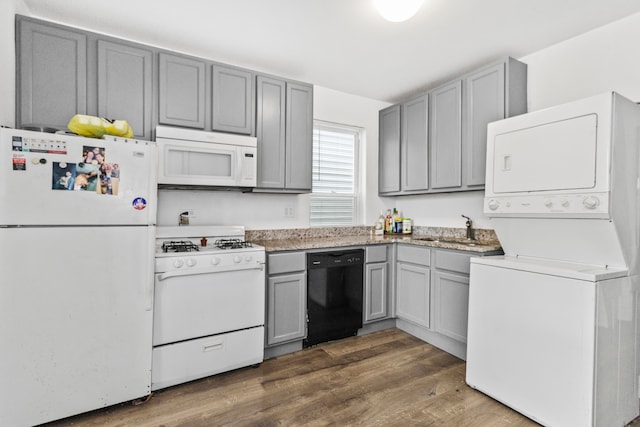 kitchen with white appliances, stacked washer / dryer, dark wood-type flooring, and gray cabinetry