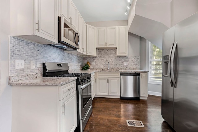 kitchen featuring white cabinets, light stone counters, stainless steel appliances, dark wood-type flooring, and sink