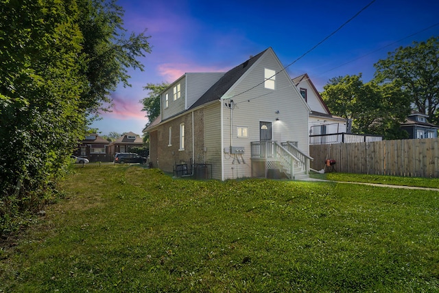 back house at dusk featuring a yard