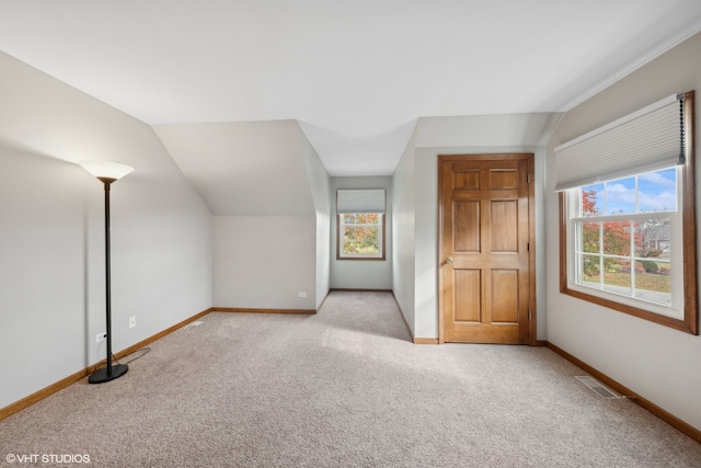 additional living space featuring vaulted ceiling and light colored carpet