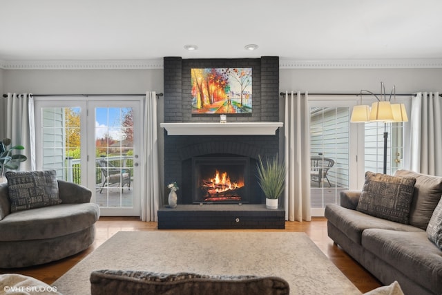 living room featuring ornamental molding, a brick fireplace, and hardwood / wood-style floors