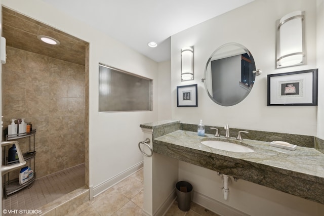 bathroom featuring a tile shower, sink, and tile patterned flooring