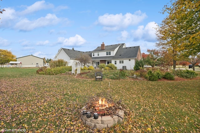 rear view of property featuring a fire pit