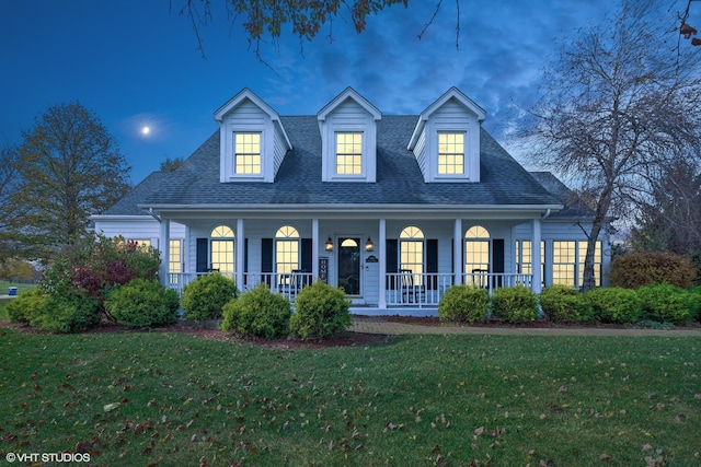 cape cod house featuring covered porch and a yard