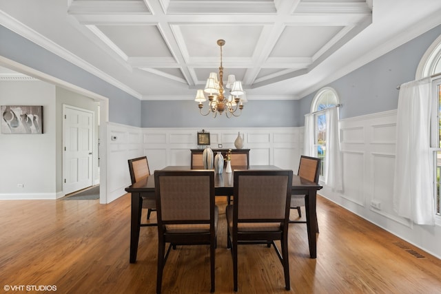 dining area with a chandelier, ornamental molding, coffered ceiling, and light hardwood / wood-style floors