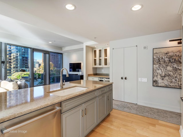 kitchen featuring gray cabinetry, dishwasher, sink, light stone counters, and light hardwood / wood-style floors