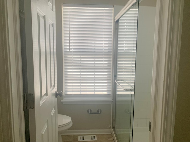 bathroom with tile patterned flooring, toilet, and a shower with shower door