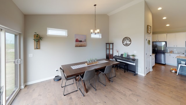 dining room featuring a notable chandelier, light hardwood / wood-style floors, and high vaulted ceiling