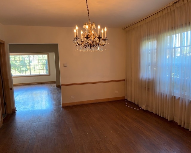 empty room featuring a notable chandelier and dark hardwood / wood-style flooring