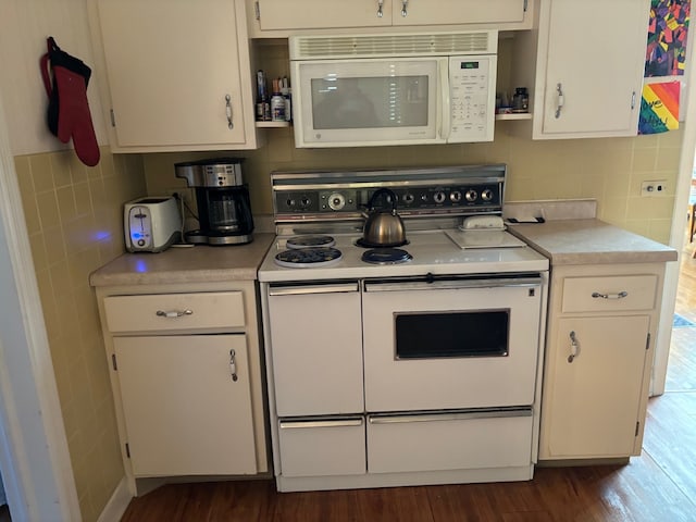 kitchen featuring dark wood-type flooring, white cabinets, decorative backsplash, and white appliances