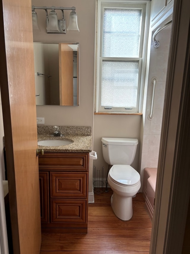 full bathroom with vanity, hardwood / wood-style floors, washtub / shower combination, and toilet