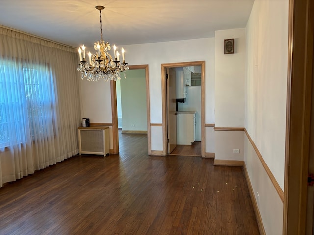 spare room with radiator heating unit, a chandelier, and dark hardwood / wood-style flooring