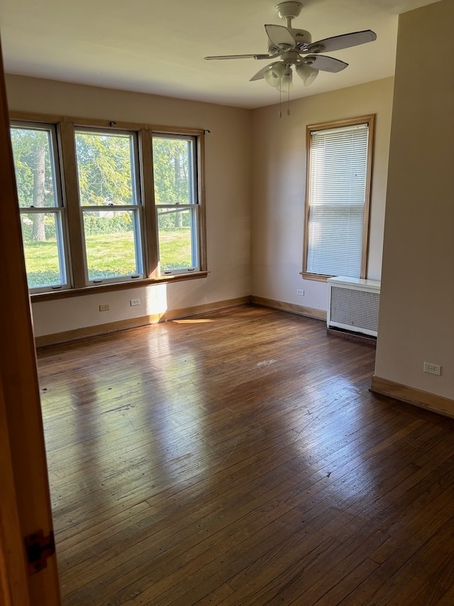 spare room featuring radiator, ceiling fan, and dark wood-type flooring