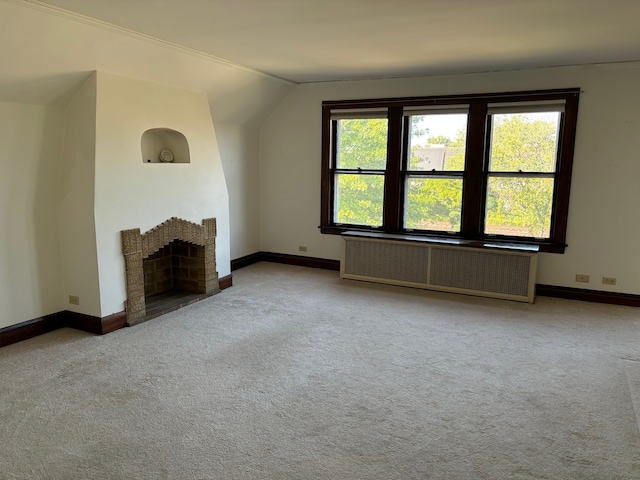 unfurnished living room with radiator, light carpet, and vaulted ceiling