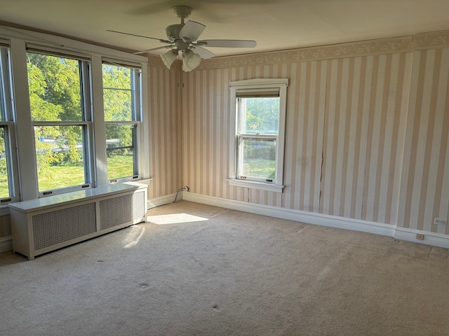 empty room featuring radiator, ceiling fan, and light colored carpet