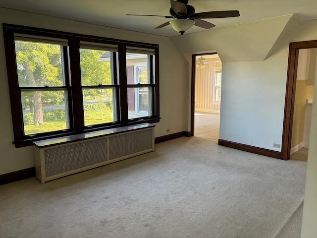 spare room with ceiling fan, vaulted ceiling, radiator heating unit, and light colored carpet