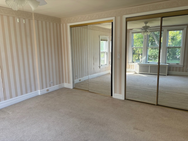 unfurnished bedroom with a closet, ceiling fan, radiator heating unit, and light colored carpet