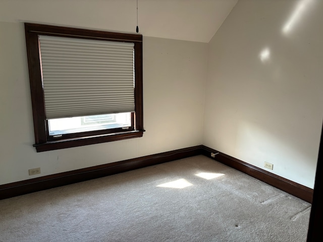 carpeted empty room with vaulted ceiling