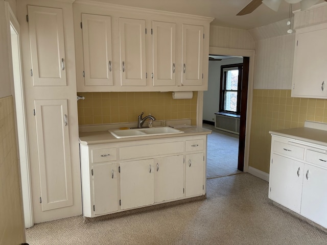 kitchen with white cabinets, ceiling fan, tile walls, sink, and light colored carpet