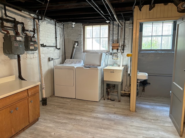 laundry area with washing machine and dryer, light hardwood / wood-style flooring, sink, and plenty of natural light