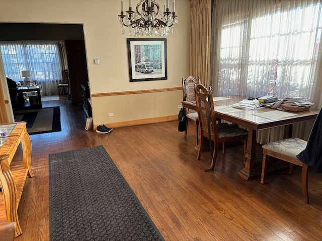 dining area featuring dark hardwood / wood-style flooring, an inviting chandelier, and a wealth of natural light