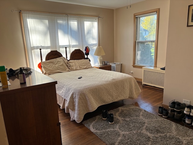 bedroom with dark hardwood / wood-style floors and radiator