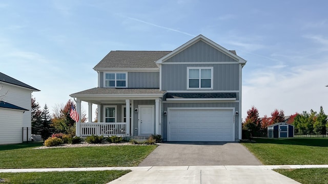 view of front facade with a front yard, a shed, a garage, and covered porch