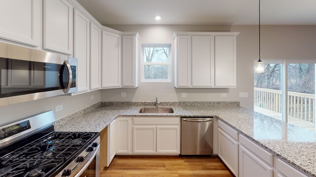 kitchen with light hardwood / wood-style flooring, appliances with stainless steel finishes, sink, and plenty of natural light