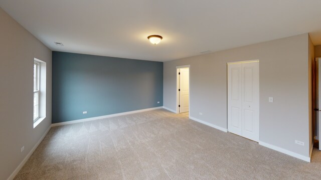 unfurnished bedroom with a closet and light colored carpet