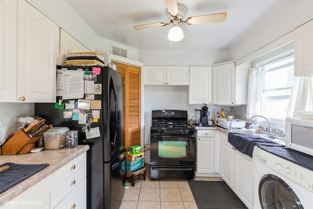 kitchen featuring washer / dryer, light tile patterned flooring, white cabinets, and black appliances