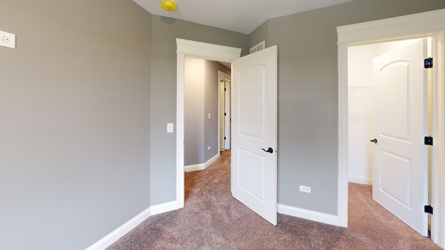 unfurnished bedroom with a closet, light colored carpet, and a walk in closet