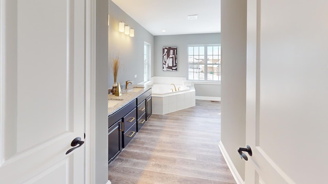 bathroom with vanity, a tub to relax in, and wood-type flooring