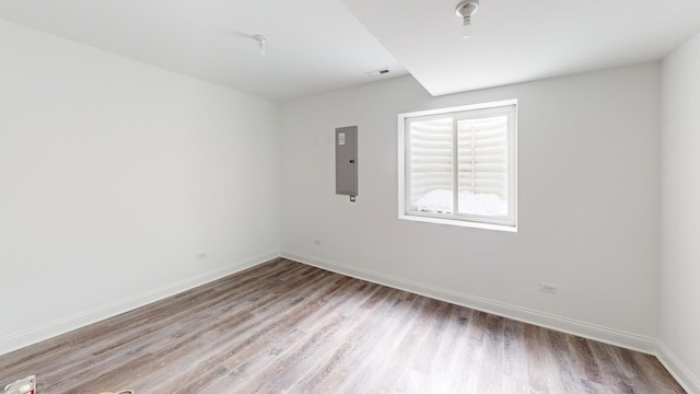 spare room featuring electric panel and light wood-type flooring