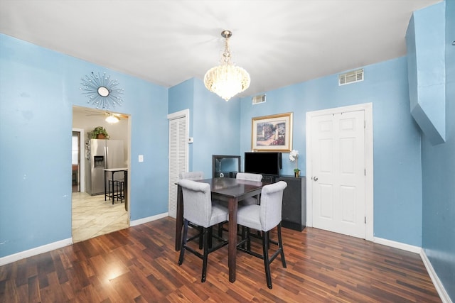 dining space with dark hardwood / wood-style floors and ceiling fan with notable chandelier